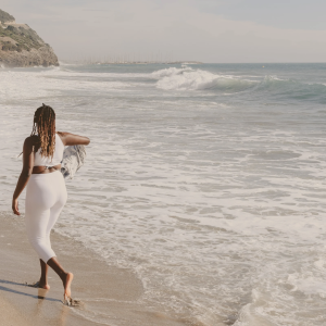 black-woman-running-on-beach-in-all-white-fertility-exercising